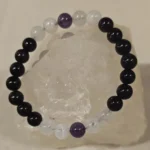 Handmade 8mm Amethyst, Rose Quartz, and Obsidian gemstone bracelet displayed on a clear quartz crystal, symbolizing protection, love, peace, and evil eye protection.