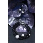 Handcrafted triple-strand Rainbow Obsidian bracelet with Swarovski crystal balls and matching sterling silver earrings displayed on decorative purple leaves.