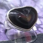 Handcrafted sterling silver ring featuring a heart-shaped Rainbow Obsidian volcanic gemstone with natural iridescent reflections.