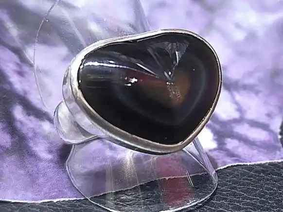 Handcrafted sterling silver ring featuring a heart-shaped Rainbow Obsidian volcanic gemstone with natural iridescent reflections.