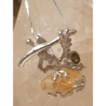 Handmade silver pendant featuring a raw golden citrine crystal and faceted smoky quartz gemstone in an organic branch-inspired setting, displayed on a crystal background.