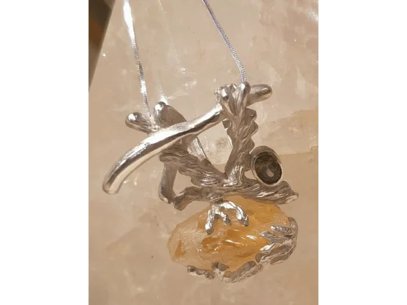 Handmade silver pendant featuring a raw golden citrine crystal and faceted smoky quartz gemstone in an organic branch-inspired setting, displayed on a crystal background.