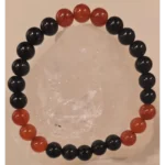 Handcrafted Obsidian and Carnelian gemstone bracelet with 8mm black and red beads displayed on a clear crystal stone, symbolizing protection, strength, and protection from the evil eye.