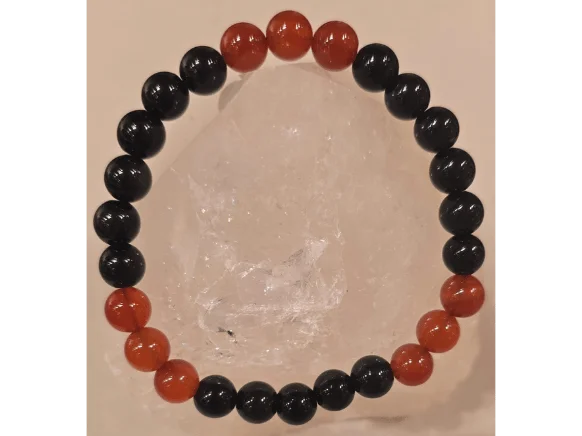 Handcrafted Obsidian and Carnelian gemstone bracelet with 8mm black and red beads displayed on a clear crystal stone, symbolizing protection, strength, and protection from the evil eye.