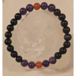 Handmade 8mm Obsidian, Amethyst, and Carnelian gemstone bracelet displayed on a clear quartz crystal, symbolizing protection, courage, spiritual balance, and evil eye defense.