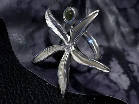 Handcrafted sterling silver flower ring featuring a natural 6mm green Peridot (Olivine) gemstone displayed on a decorative dark background.
