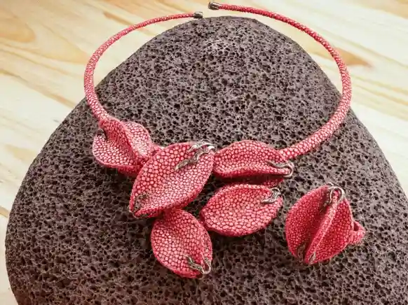 Handcrafted red stingray leather choker necklace with matching ring displayed on a volcanic stone.