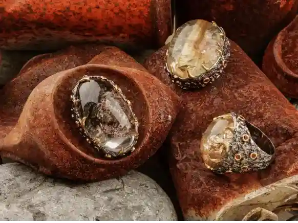 Handcrafted sterling silver lodolite pendants and black silver lodolite ring with natural Garden Quartz gemstones displayed on rustic stones.