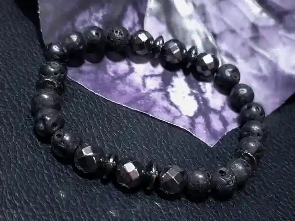 Handcrafted volcanic lava stone and hematite bracelet with natural 8mm black gemstone beads displayed on a dark background.